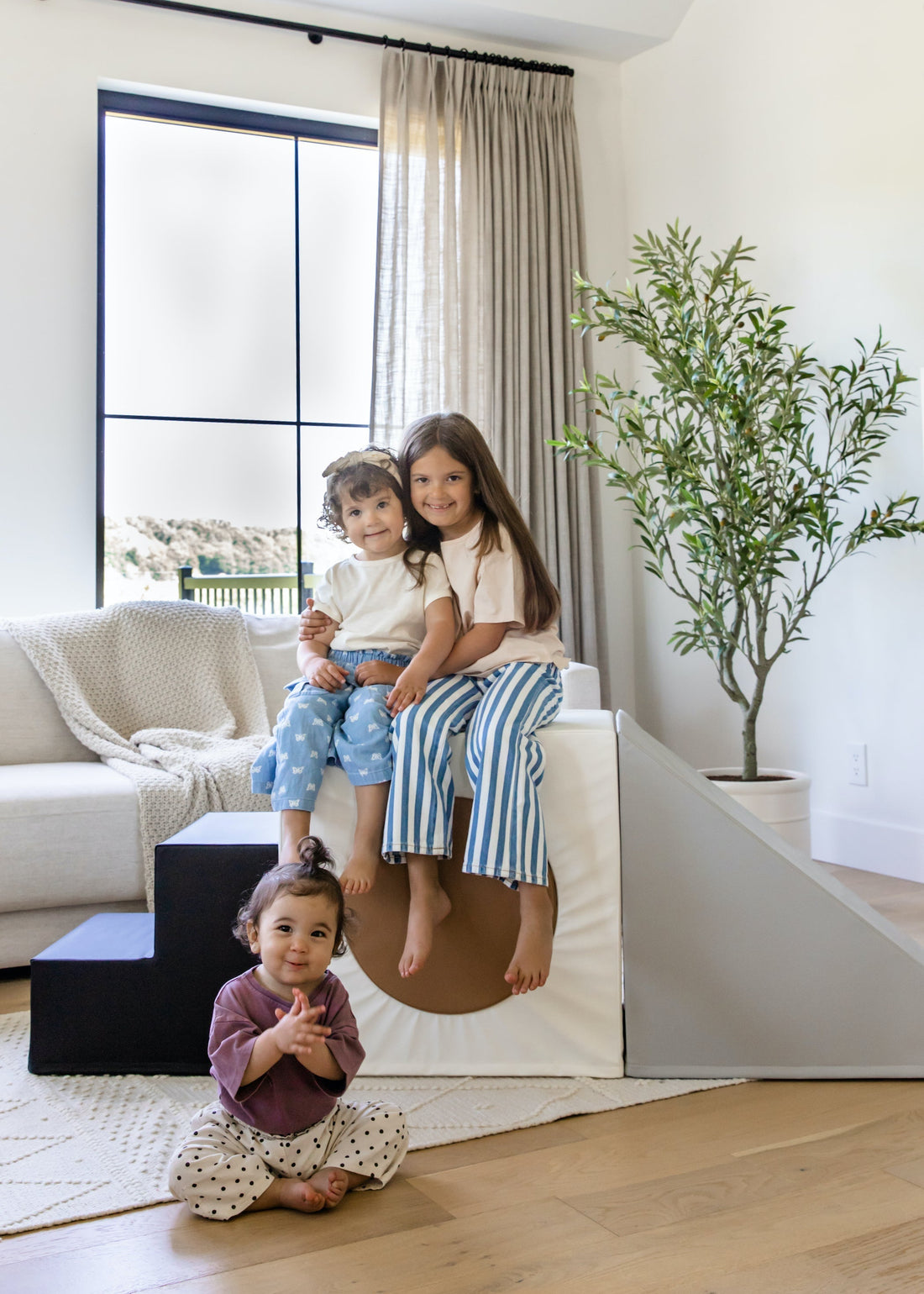 Toddler playing on North&Nova foam climber while parent watches in modern living room